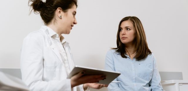 Clinical practitioner in a white lab coat holding a tablet during a patient consultation for lifestyle and practical psychology counseling
