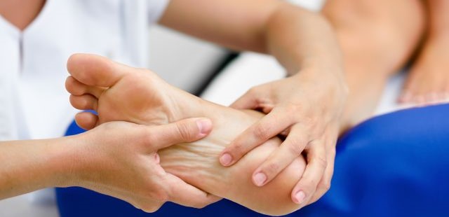 Practitioner applying targeted physical mobilization pressure to a patient's plantar fascia and heel zone to treat foot conditions