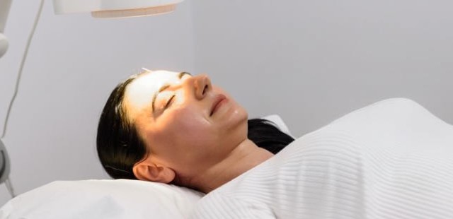 A female patient receiving infrared heat therapy essex combined with targeted head acupuncture needles to treat chronic systemic conditions